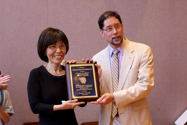 Professor Yu holding a plaque.