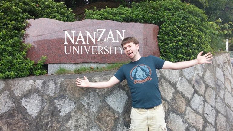 Nathaniel Guy in front of a Nan Zan Univeristy sign.