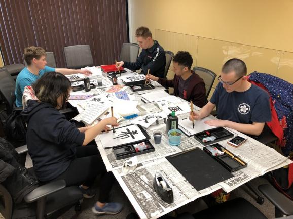 Students practicing Japanese calligraphy.