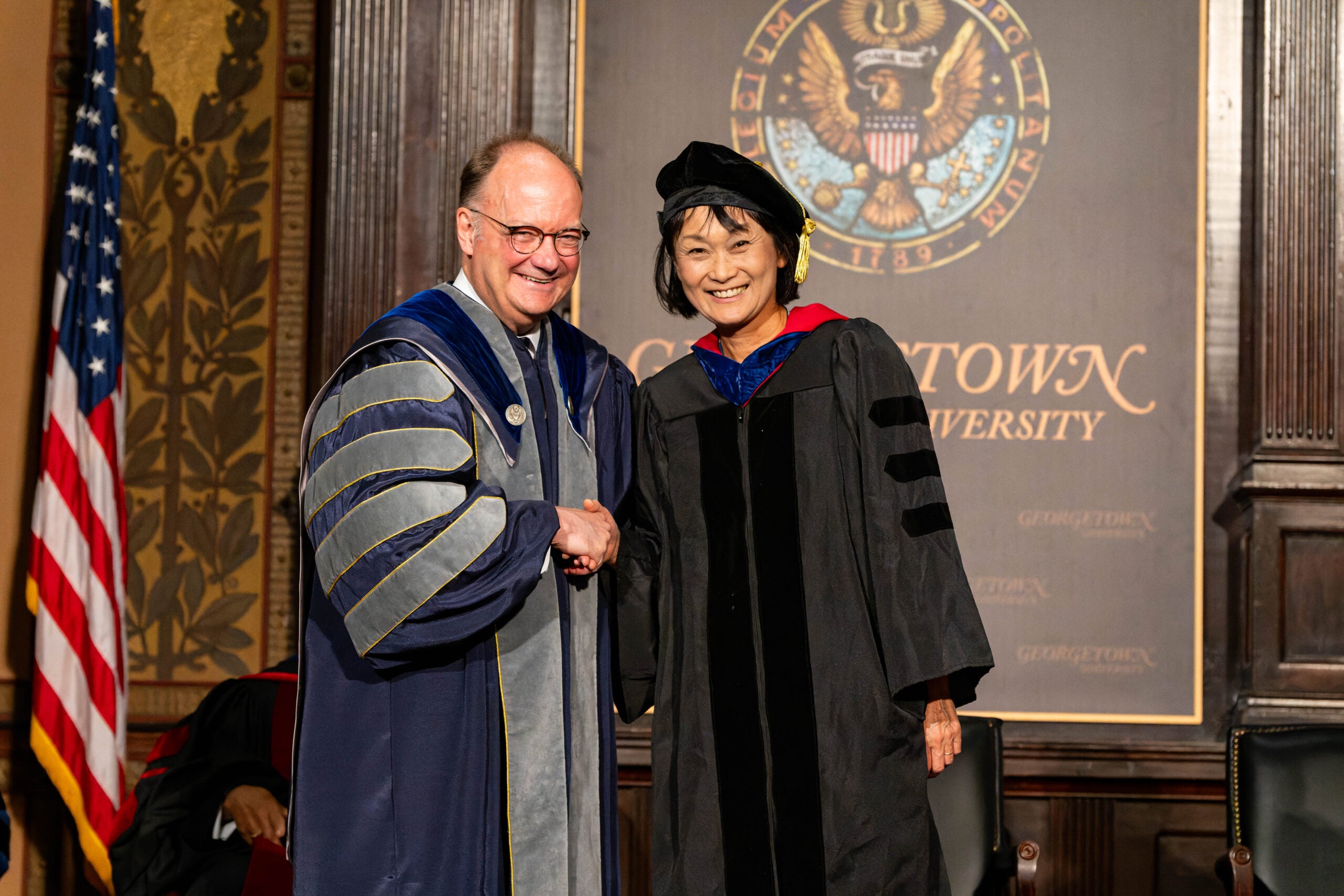 Georgetown University professors and president shake hands at ceremony